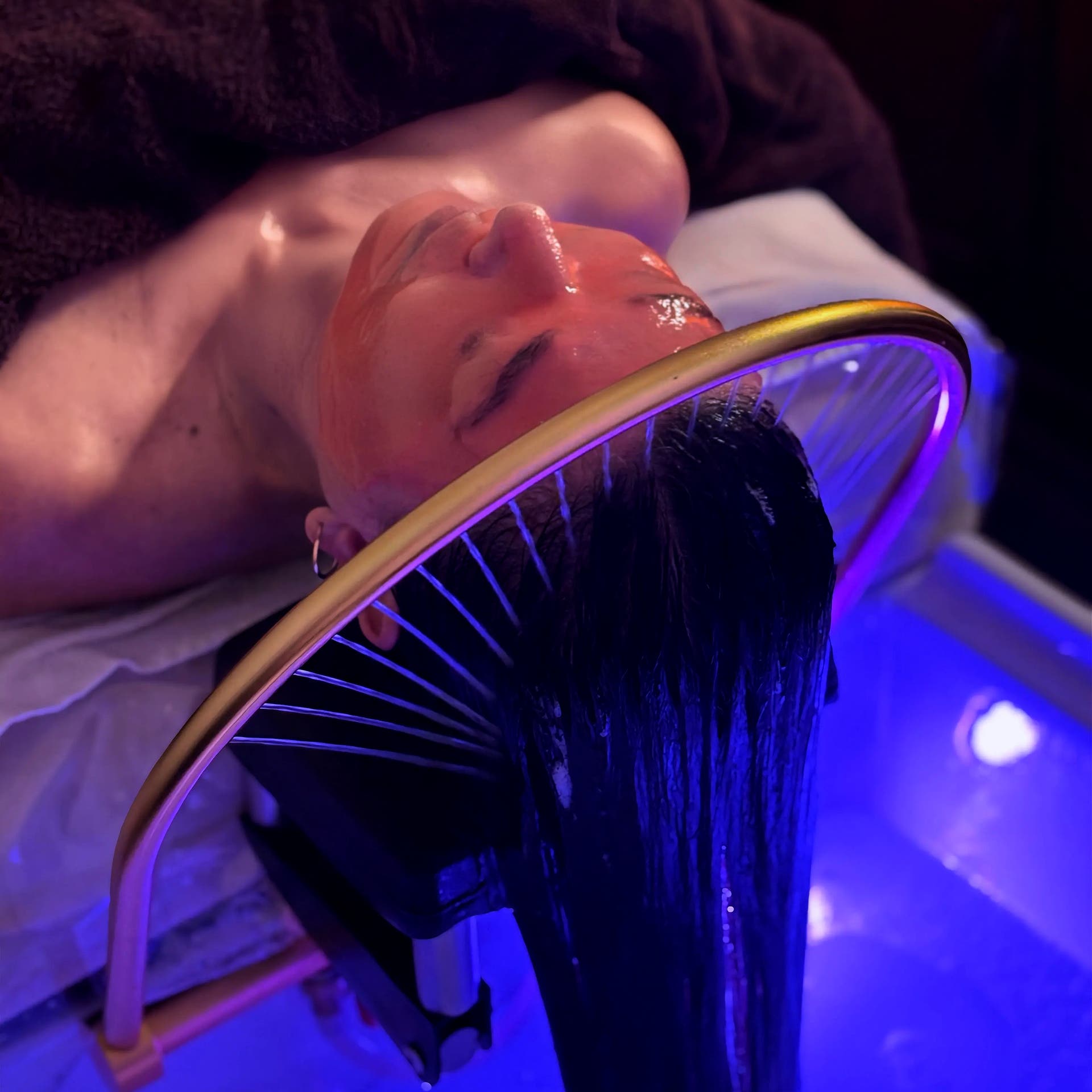 A head spa treatment in progress at SHE Day Spa, with the client's hair fanned out over the lit basin halo
