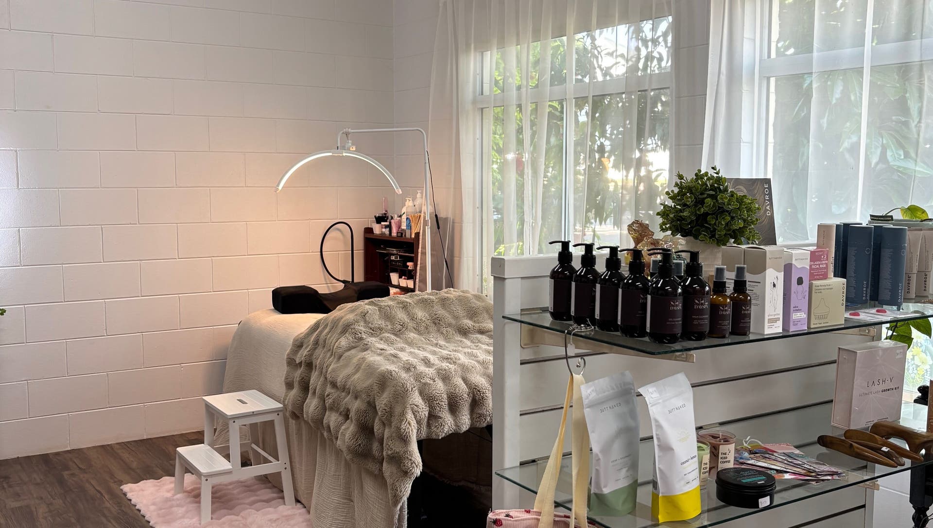 The treatment room at SHE Day Spa, with the bed made up under a soft throw and the retail shelves by the window